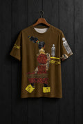 A brown short-sleeve t-shirt hanging on a wooden hanger against a light gray wall. The shirt features a large graphic print of a woman in traditional attire with red and black patterns, yellow shoes, and gold script, alongside small gray Buddha statues.